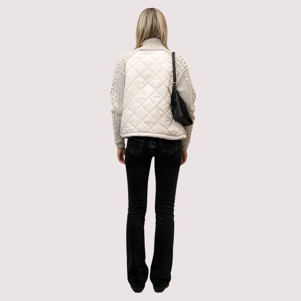 Woman wearing the Kouvr Mika khaki quilted jacket with cable knit sleeves, styled with black jeans