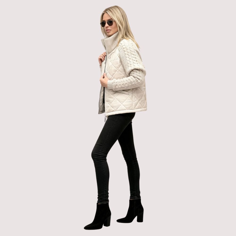 Woman wearing the Kouvr Mika khaki quilted jacket with cable knit sleeves, styled with black jeans