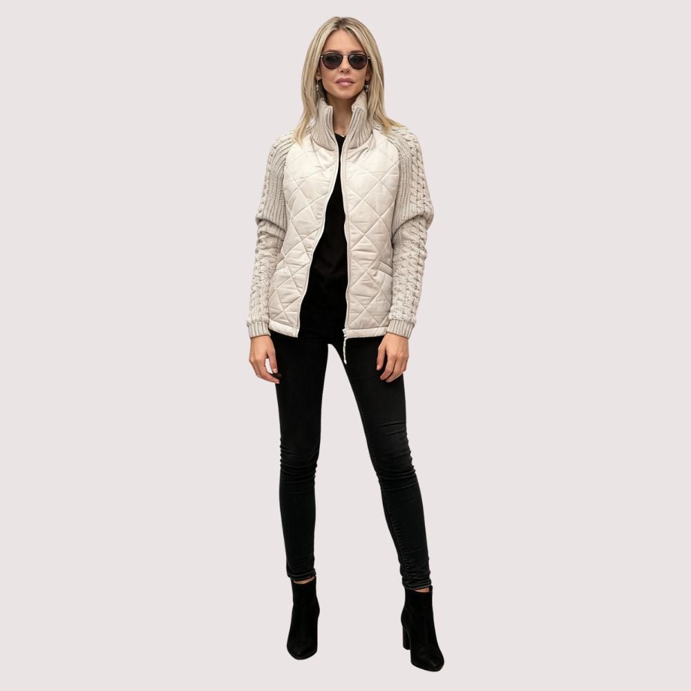 Woman wearing the Kouvr Mika khaki quilted jacket with cable knit sleeves, styled with black jeans