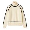 Product shot of a women's cream turtleneck sweater with black piping detail along the funnel neck, raglan sleeves, and body.