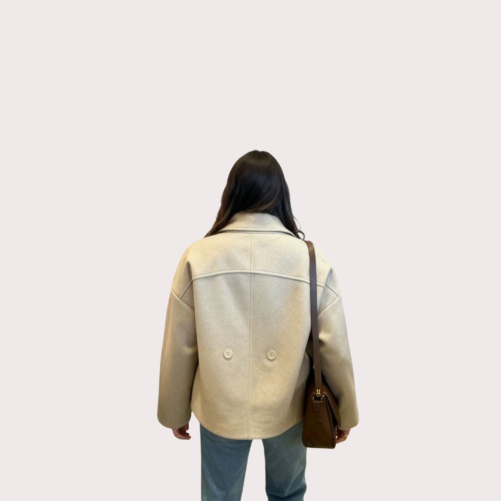 Model wearing the Kouvr oversized oatmeal wool jacket with blue jeans and a brown shoulder bag