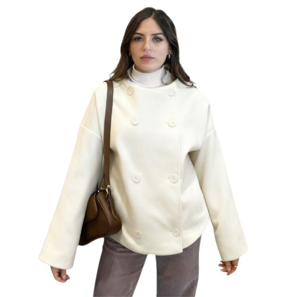Model wearing the Niana short coat in ivory, styled with a white turtleneck and brown shoulder bag