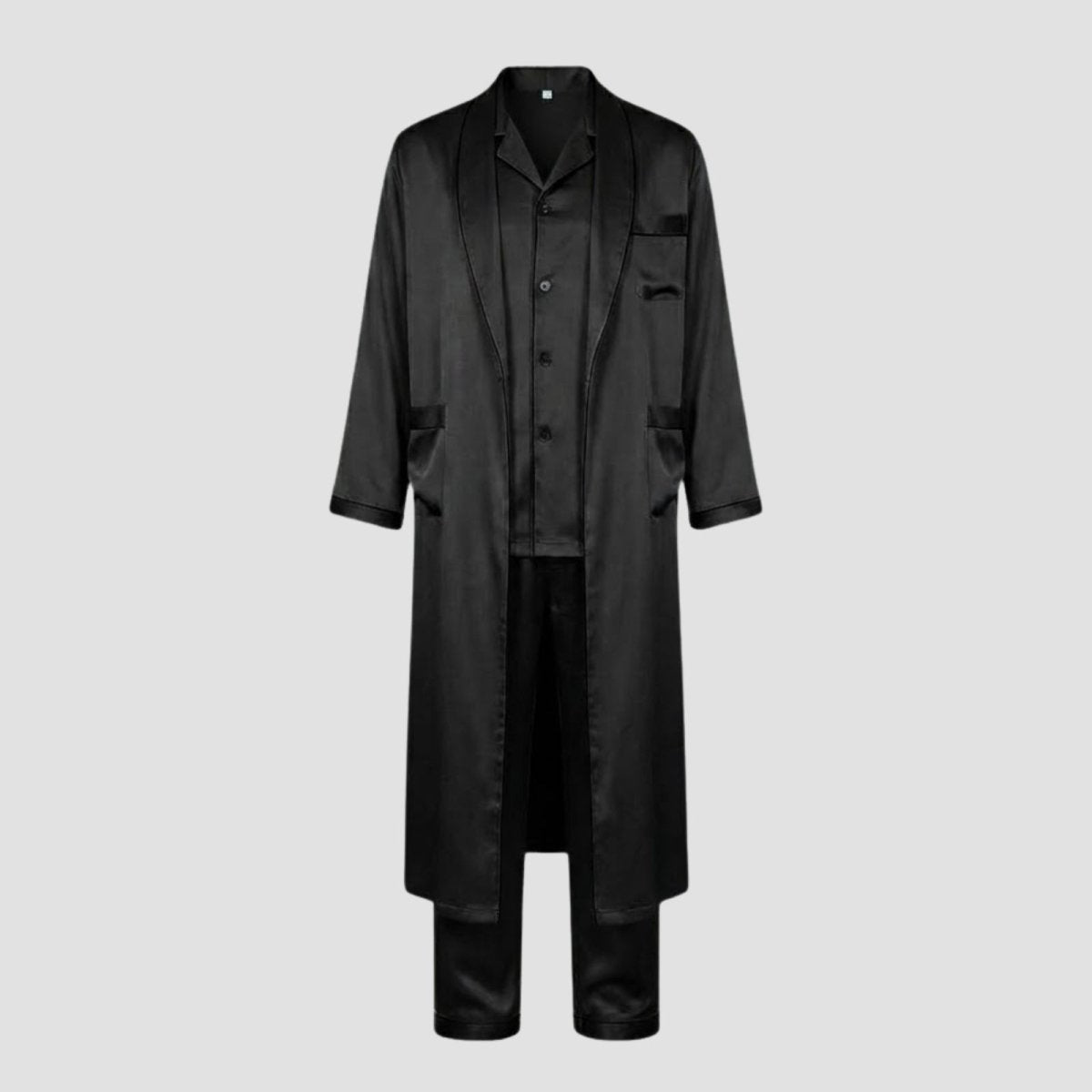 Flatlay product shot of the Kouvr black silk pajama shirt, pants, and long robe set against a light grey background.