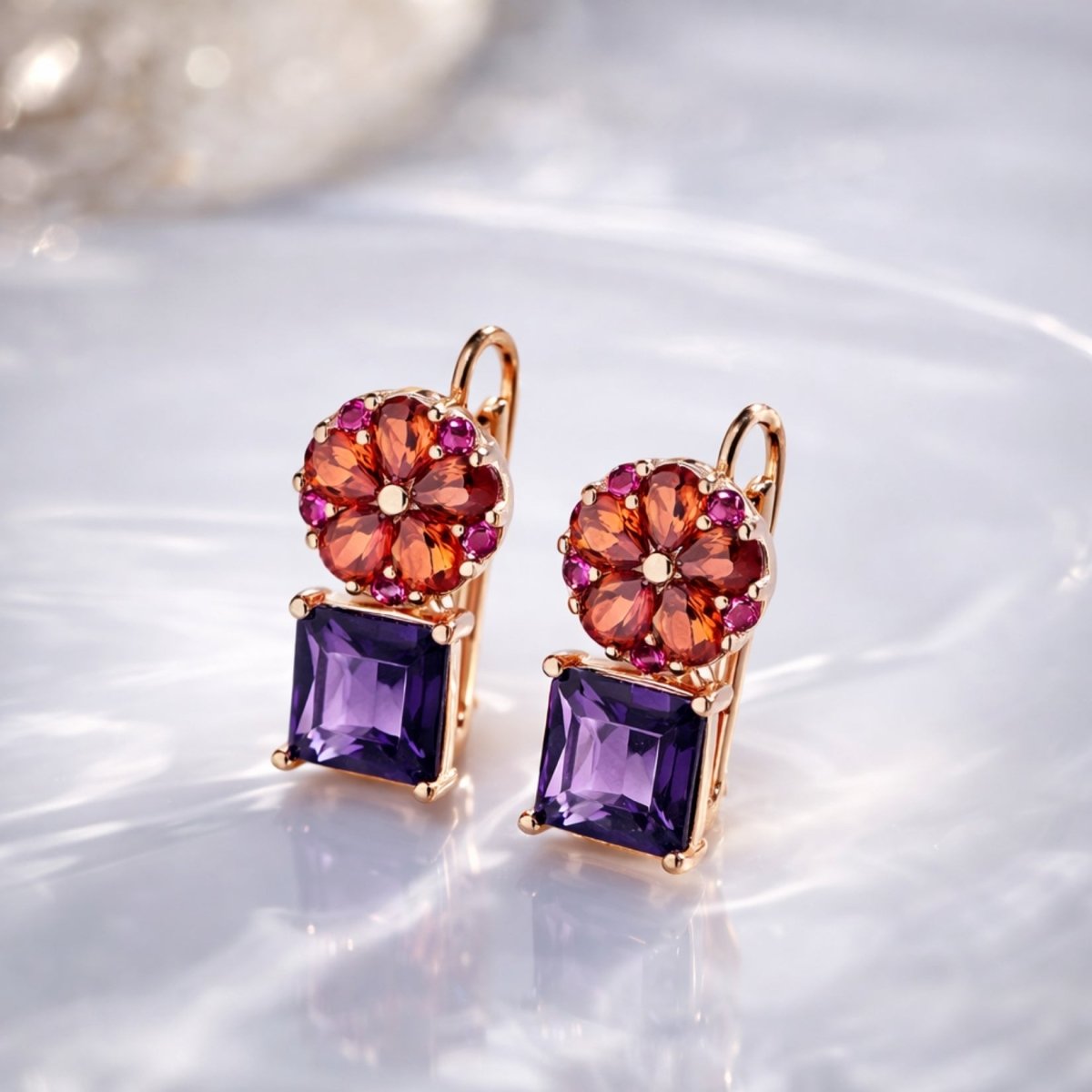 Kouvr octivia amethyst and garnet drop earrings in rose gold resting on a sunlit marble surface.