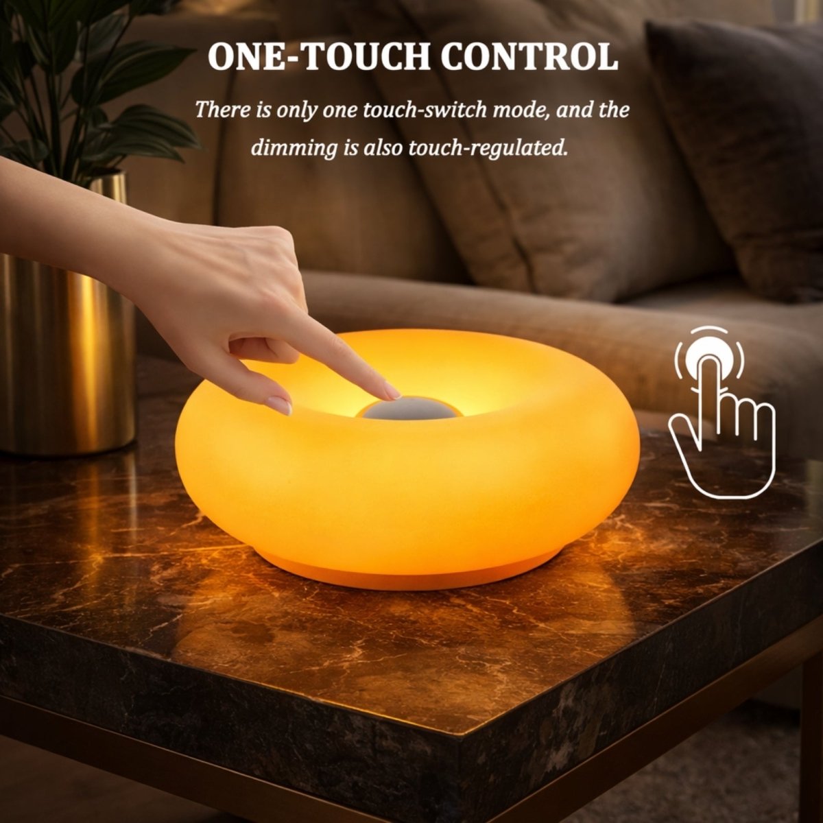 Hand adjusting brightness on Kouvr orange donut table lamp with touch sensor control, glowing warm amber light on marble side table.
