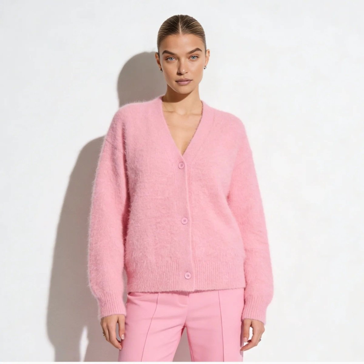 Model wearing the Kouvr pink fluffy v-neck cardigan with matching trousers against a white background.