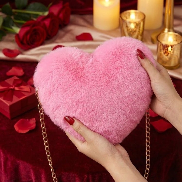 Close-up detail shot of a woman's hands with red nails holding the soft, fluffy pink heart-shaped faux fur bag against a romantic, candlelit backdrop.
