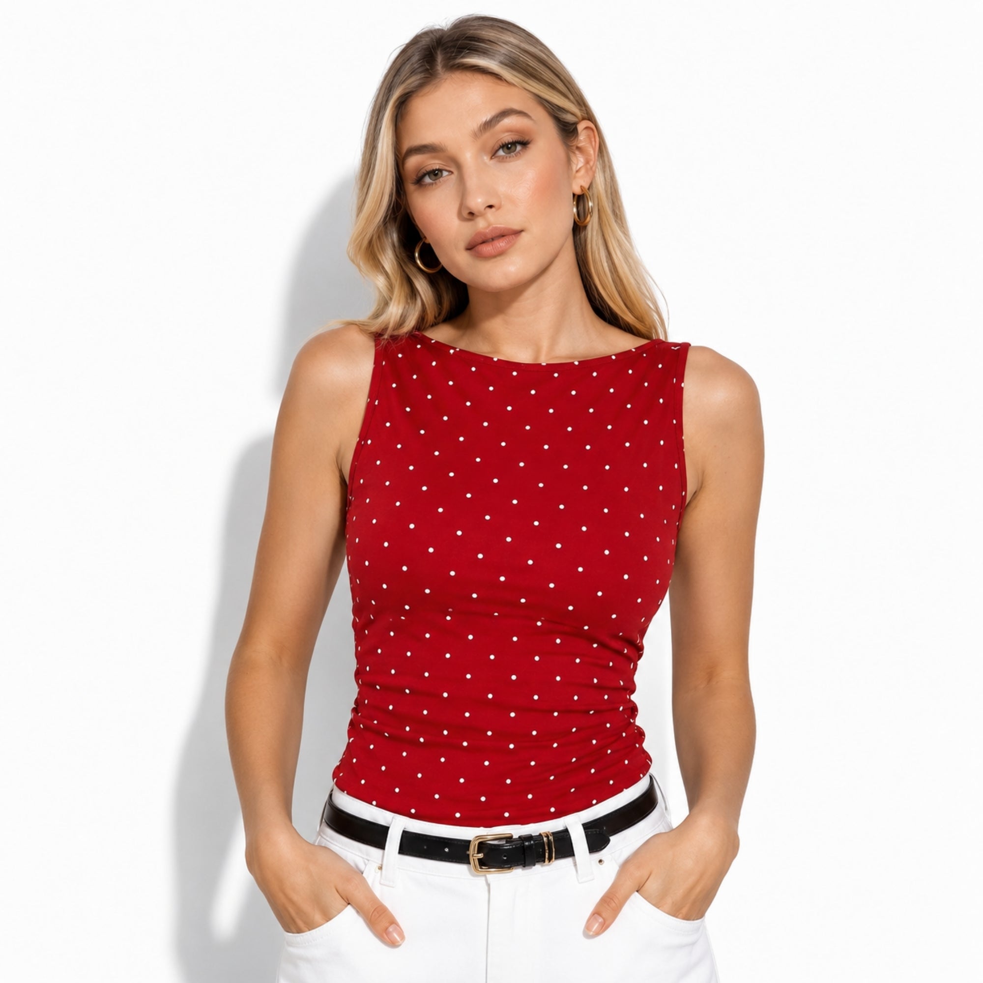 Woman wearing Kouvr crimson red polka dot top with ruched detailing, perfectly paired with white denim and a black belt.