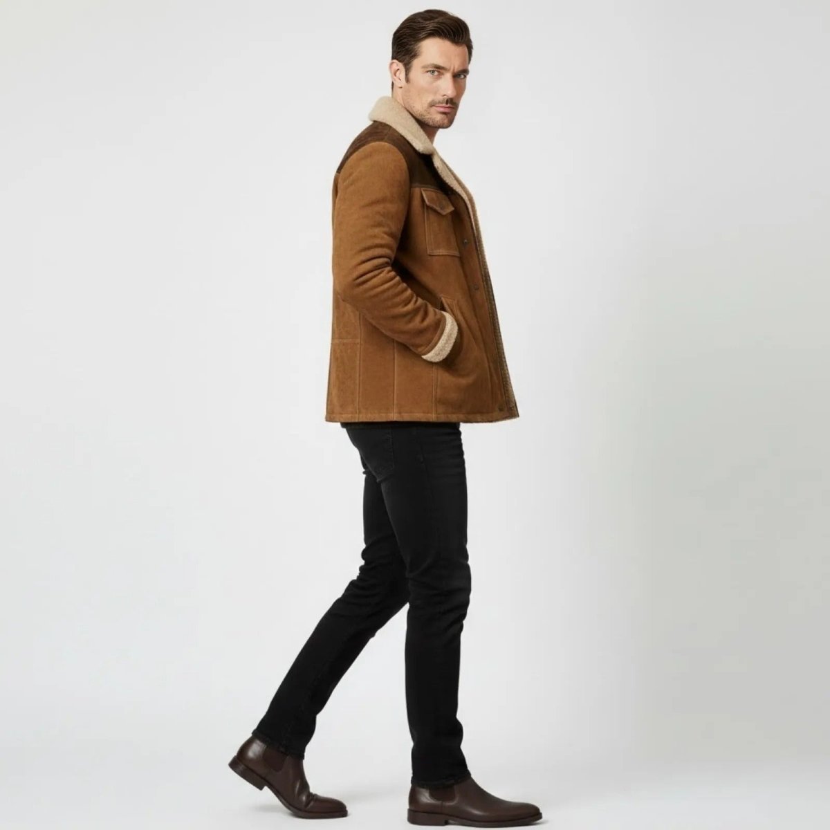 Side profile of a man walking in the Kouvr Porter cognac suede shearling jacket showing its fit and length.