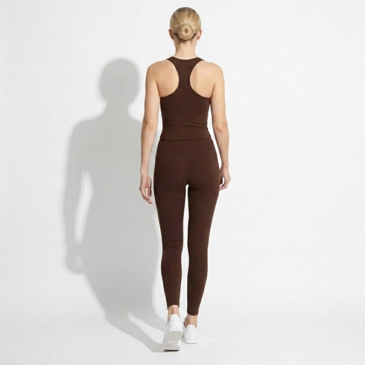 Model walking away wearing Kouvr premium athletic wear brown set showing seamless fit