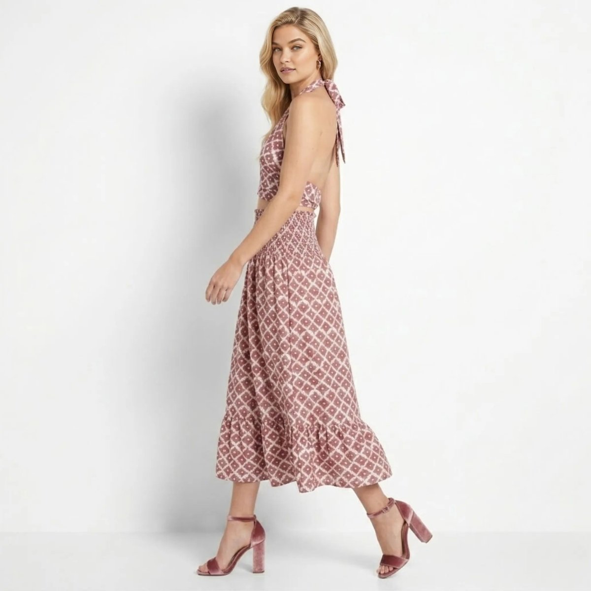 Side profile of woman walking in Kouvr red vacation matching skirt set showing back tie and open back detail.