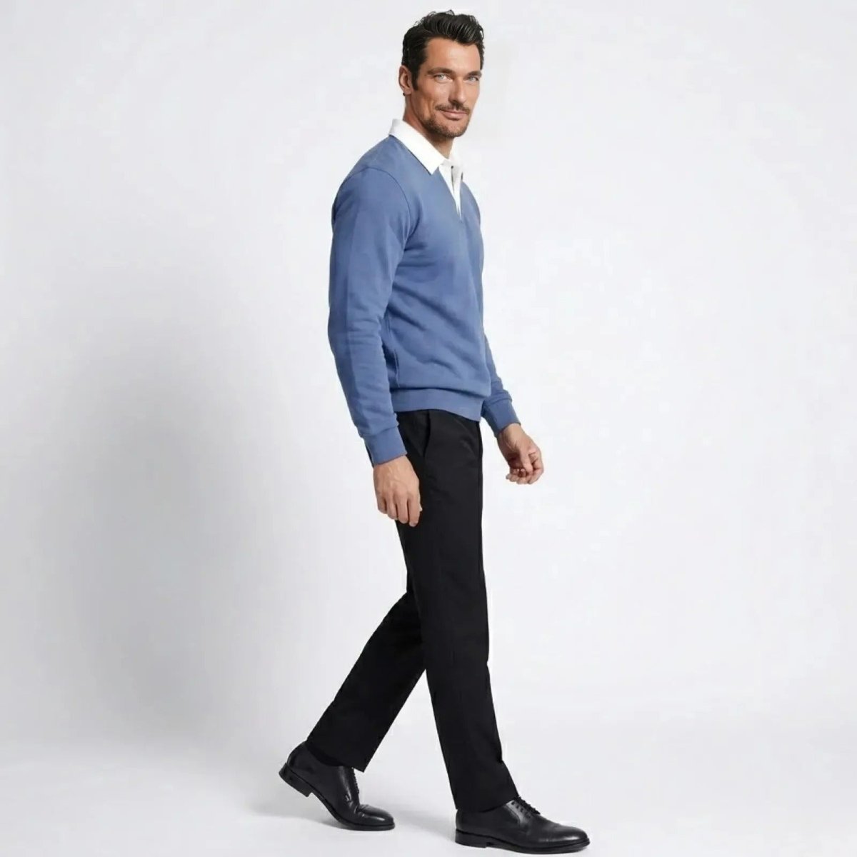 Side profile of a man walking while wearing the steel blue Kouvr Rhodes polo sweater, showcasing its tailored fit and drape.