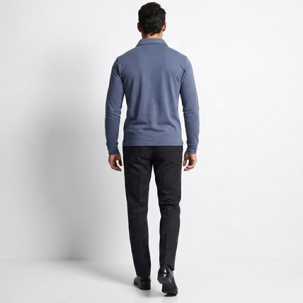 Back view of a man wearing the Kouvr Rome Long Sleeve Polo in slate blue and dark trousers, showing the fit across the shoulders.