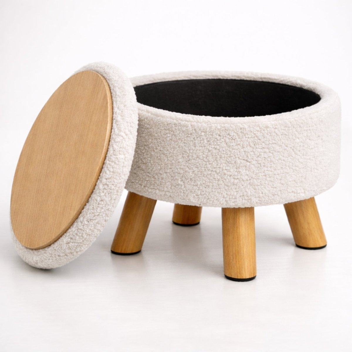 White round bouclé storage ottoman with its reversible wood tray lid leaning against it, shown on a clean white background.