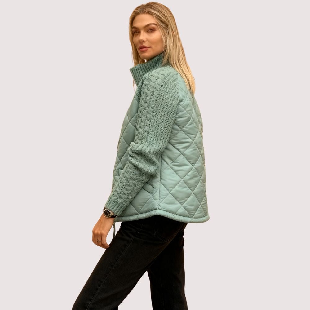 Model wearing Kouvr sage green quilted jacket with cable knit sleeves, viewed from the front
