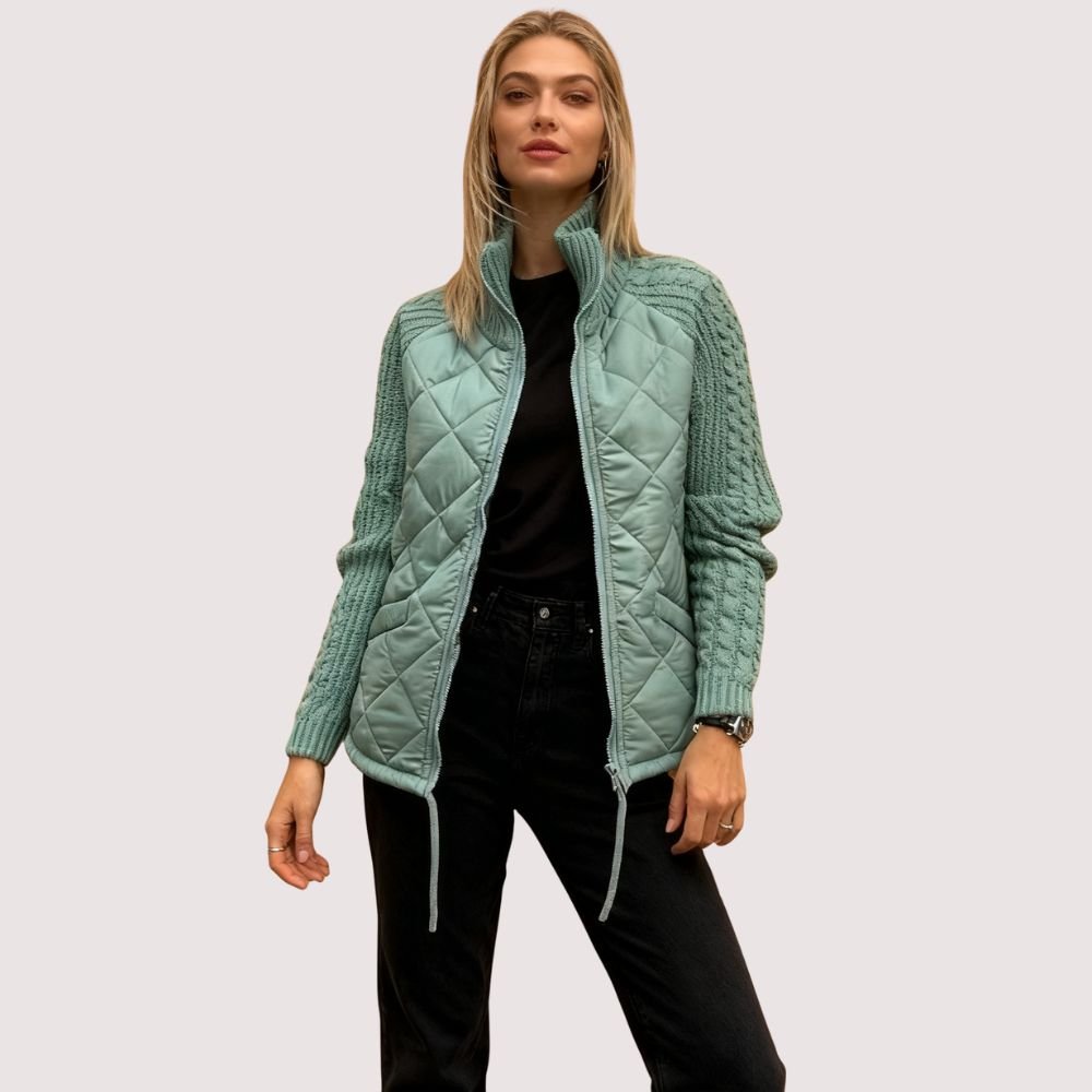 Model wearing Kouvr sage green quilted jacket with cable knit sleeves, viewed from the front