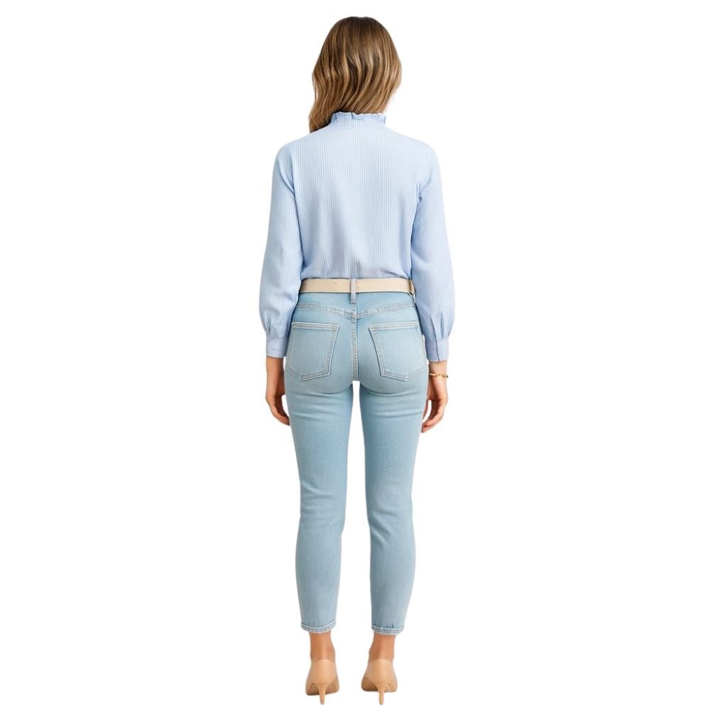 Woman wearing the Kouvr Shandee blue long sleeve ruffle blouse tucked into light wash jean