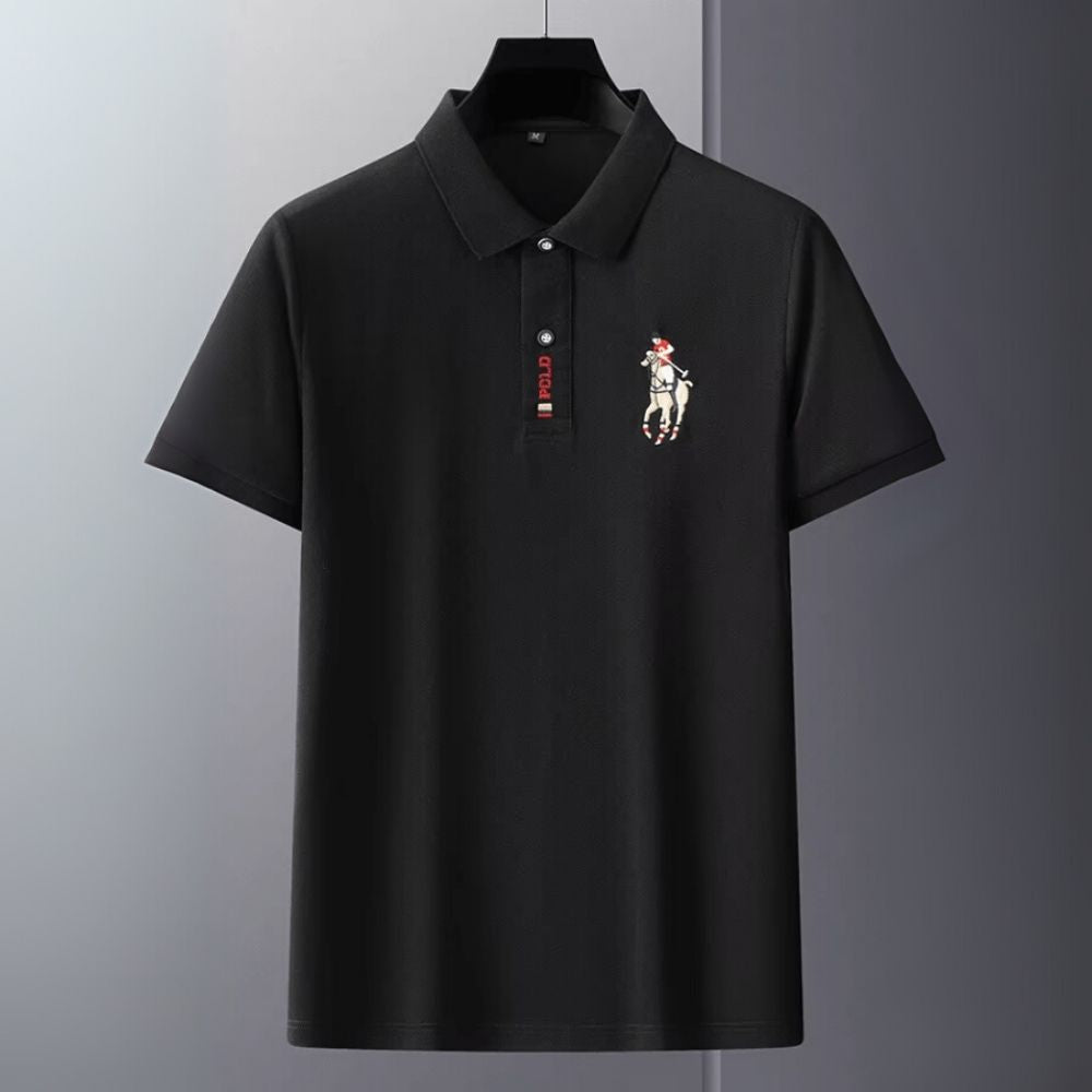 Black kouvr polo shirt with a small logo on a gray background