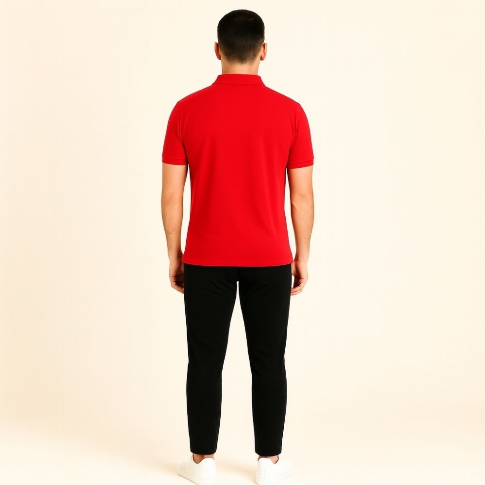 Person wearing a red kouvr polo shirt and black pants on a beige background