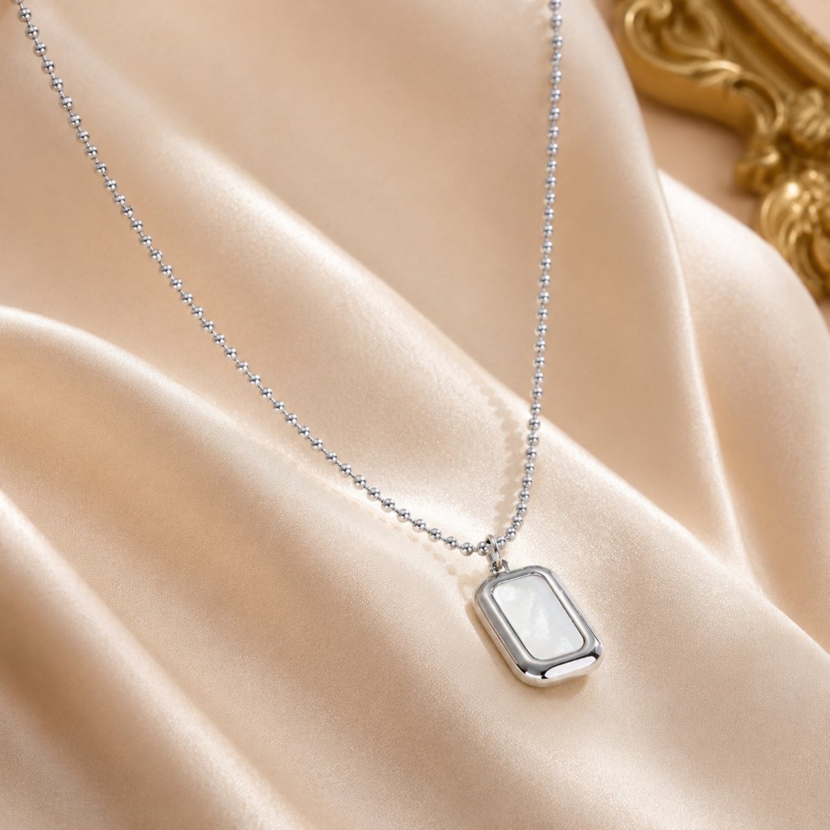 Close up of luxury silver rectangular mother of pearl necklace showcased on smooth silk backdrop