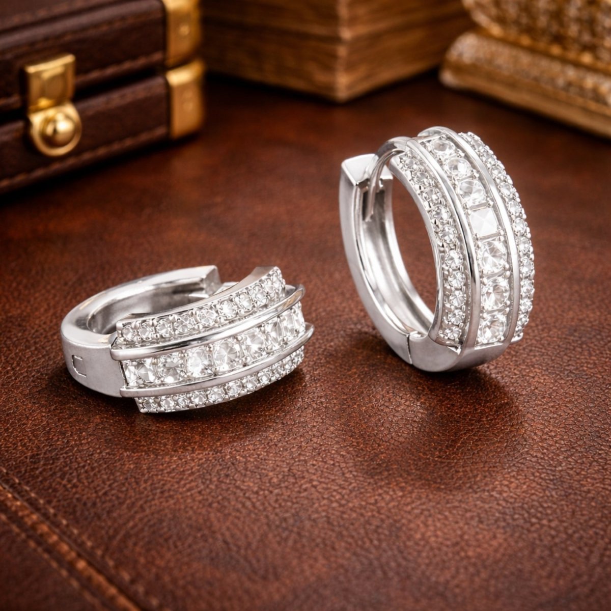 Angled detail shot of the Kouvr sterling silver huggie hoop earrings, highlighting the channel-set princess cut stones and pavé detailing.