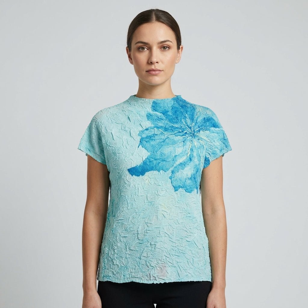 Close up of high neck blue plisse designer top featuring oversized watercolor blue flower applique design