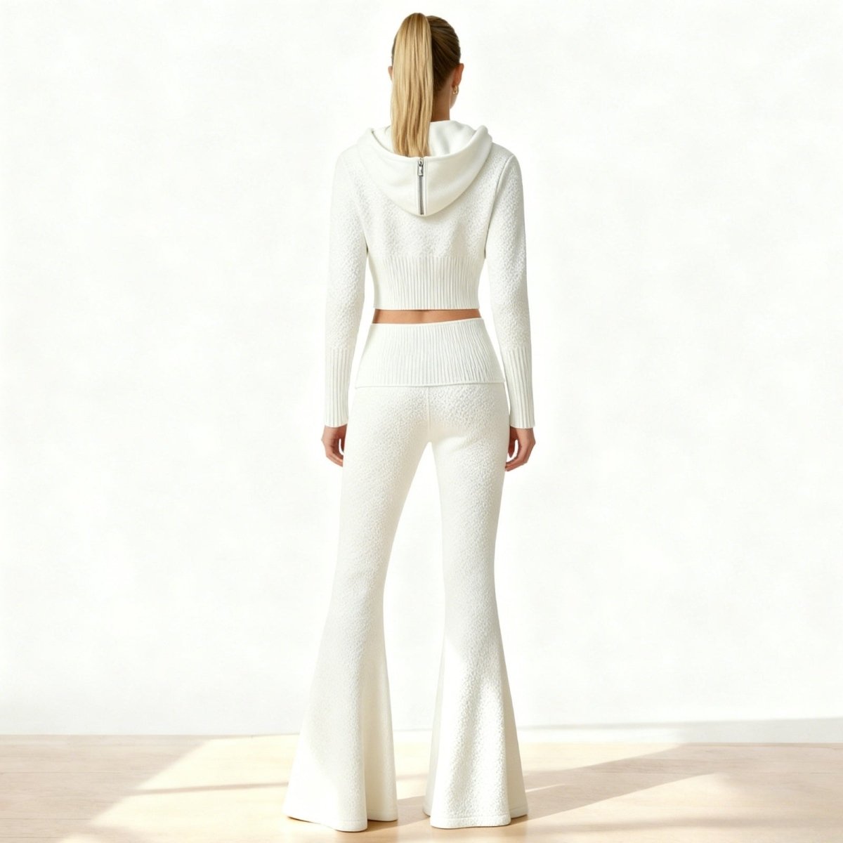 Back view of the Kouvr Stella two-piece set in white, showcasing the textured jacquard knit and the fit of the hoodie and flared pants.