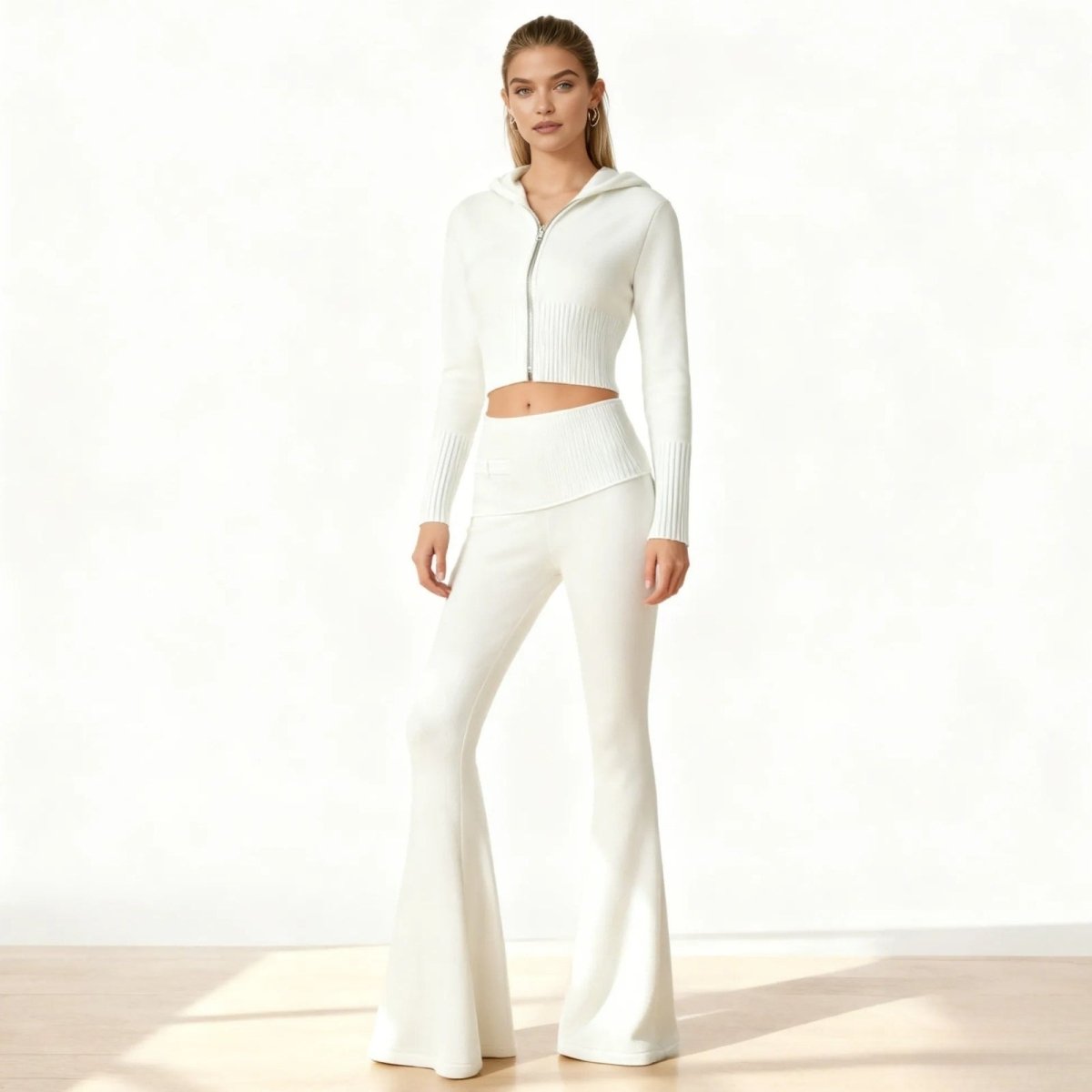 Model wearing the white Stella knit set by Kouvr Fashion, a two-piece outfit with a cropped zip hoodie and high-waisted flared pants.