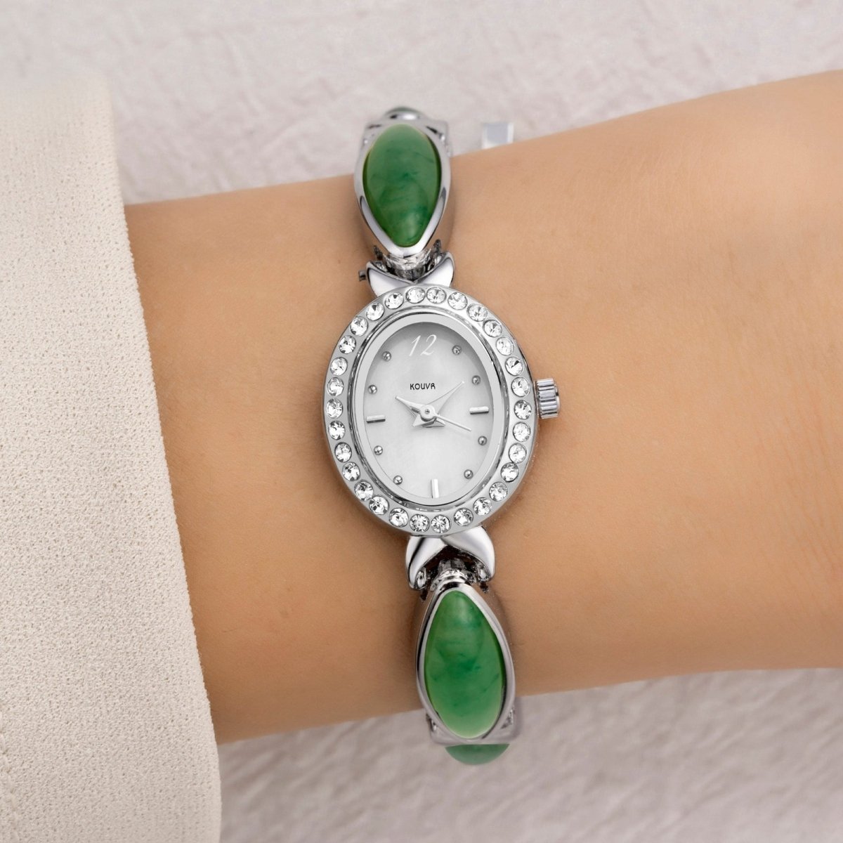 A woman wearing the elegant Kouvr Tiger's Eye and silver green bracelet watch, paired with a white sleeve