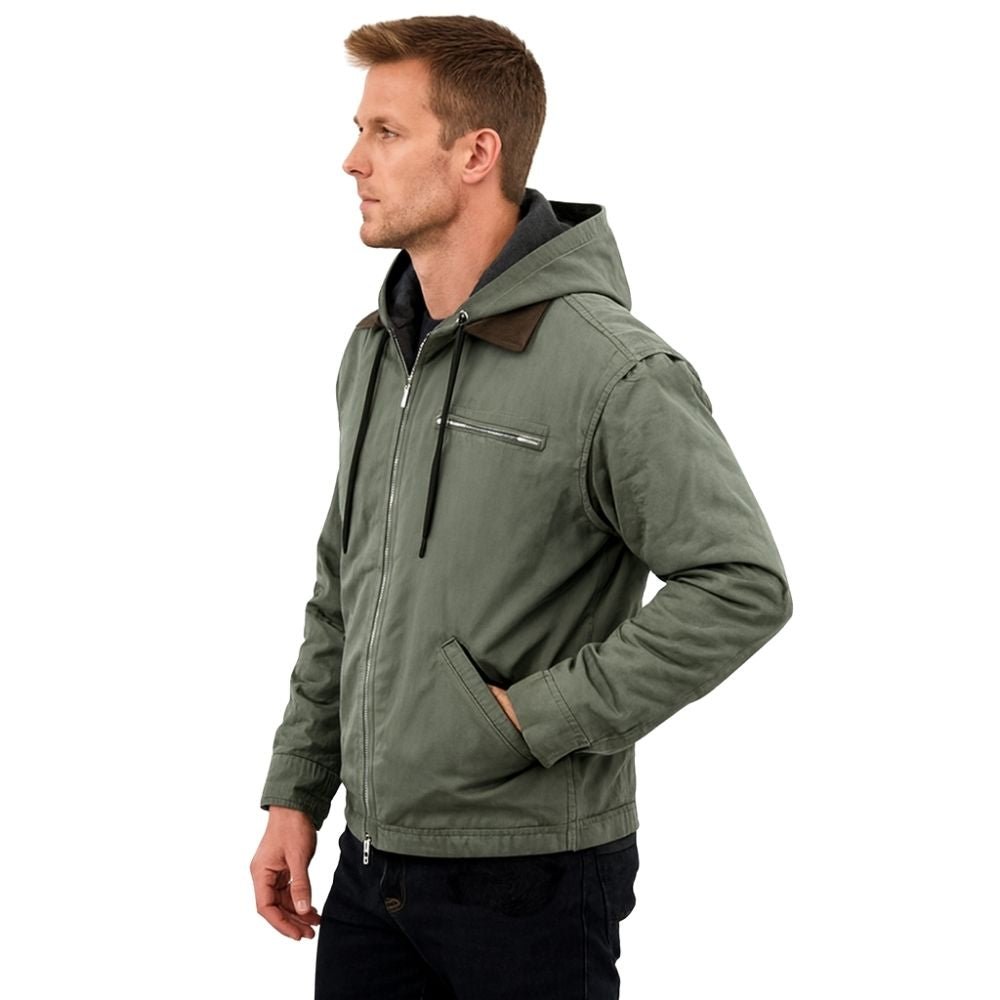 Man wearing the Kouvr tyrian sherpa-lined olive green canvas hooded jacket, facing side with hands in pockets.