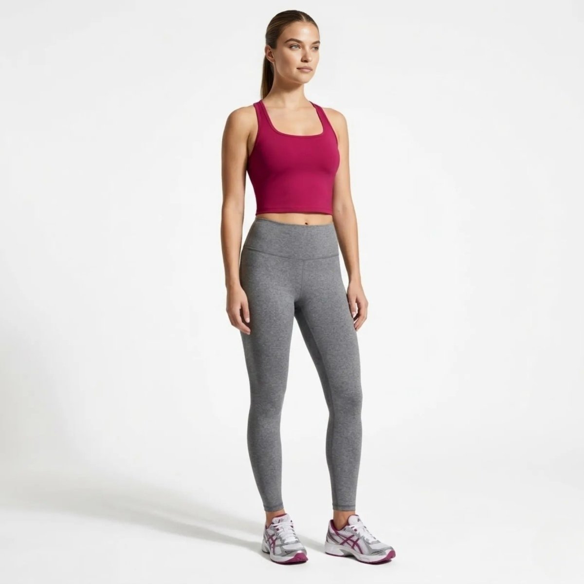 Side angle view of model modeling the Kouvr vibrant pink fitness tank top and high-waisted leggings outfit