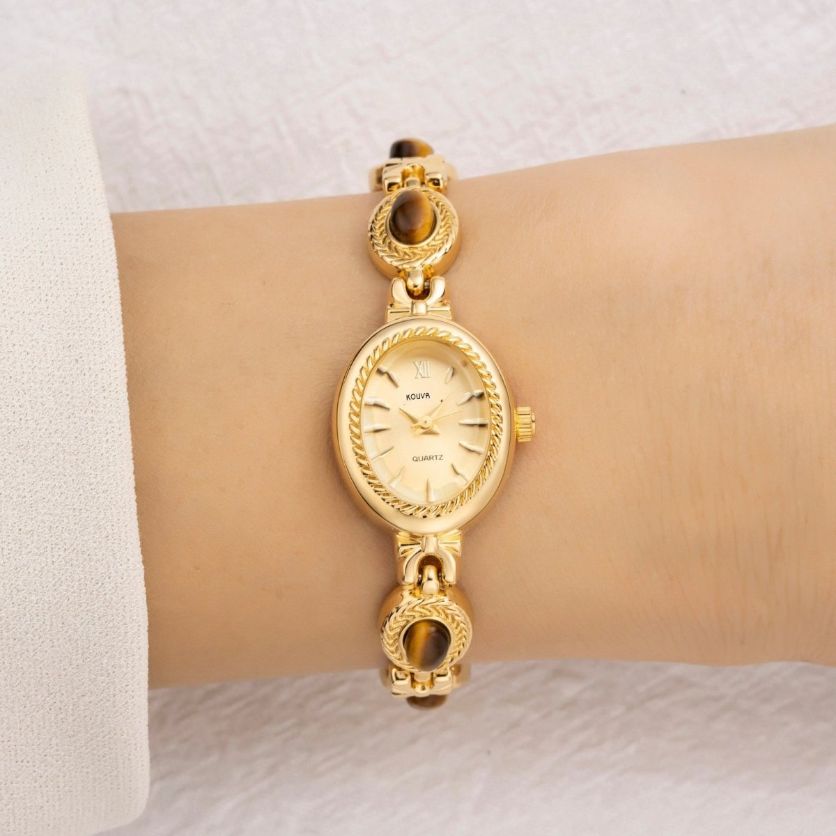 Gold kouvr wristwatch on a wrist with a white background
