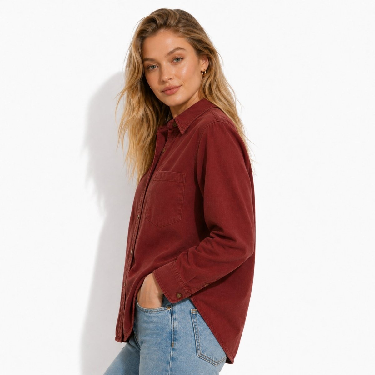 Side profile of the Kouvr vintage wash red oversized shirt highlighting the curved shirttail hem and relaxed fit on a blonde female model.