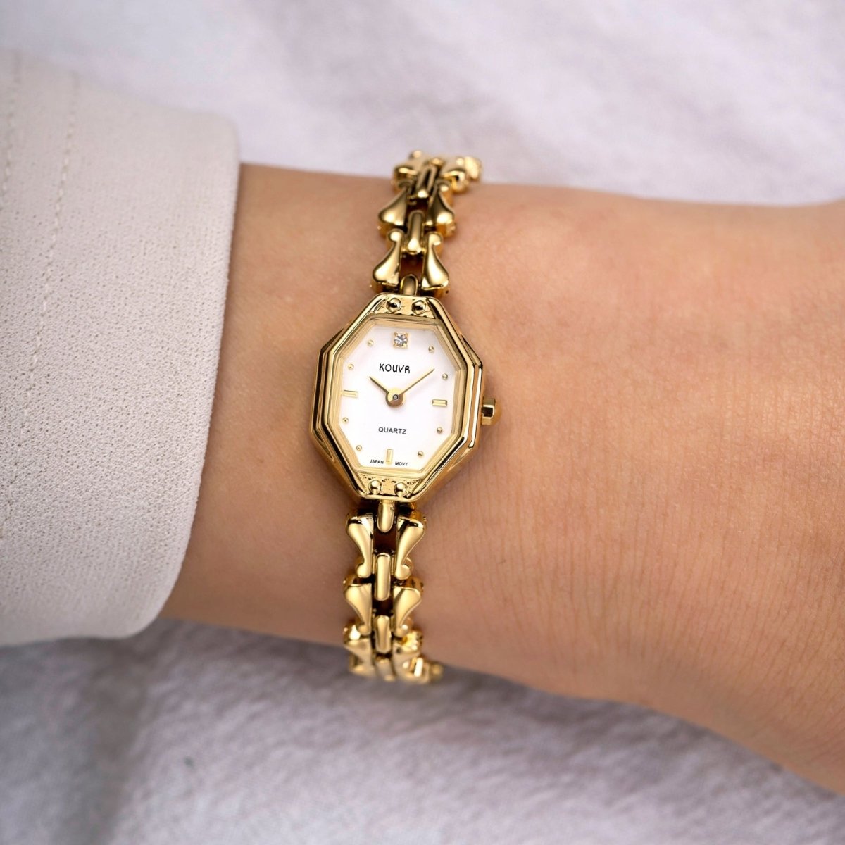 A woman wearing the dainty Kouvr vintage white gold kouvr bracelet watch, paired with a white blouse