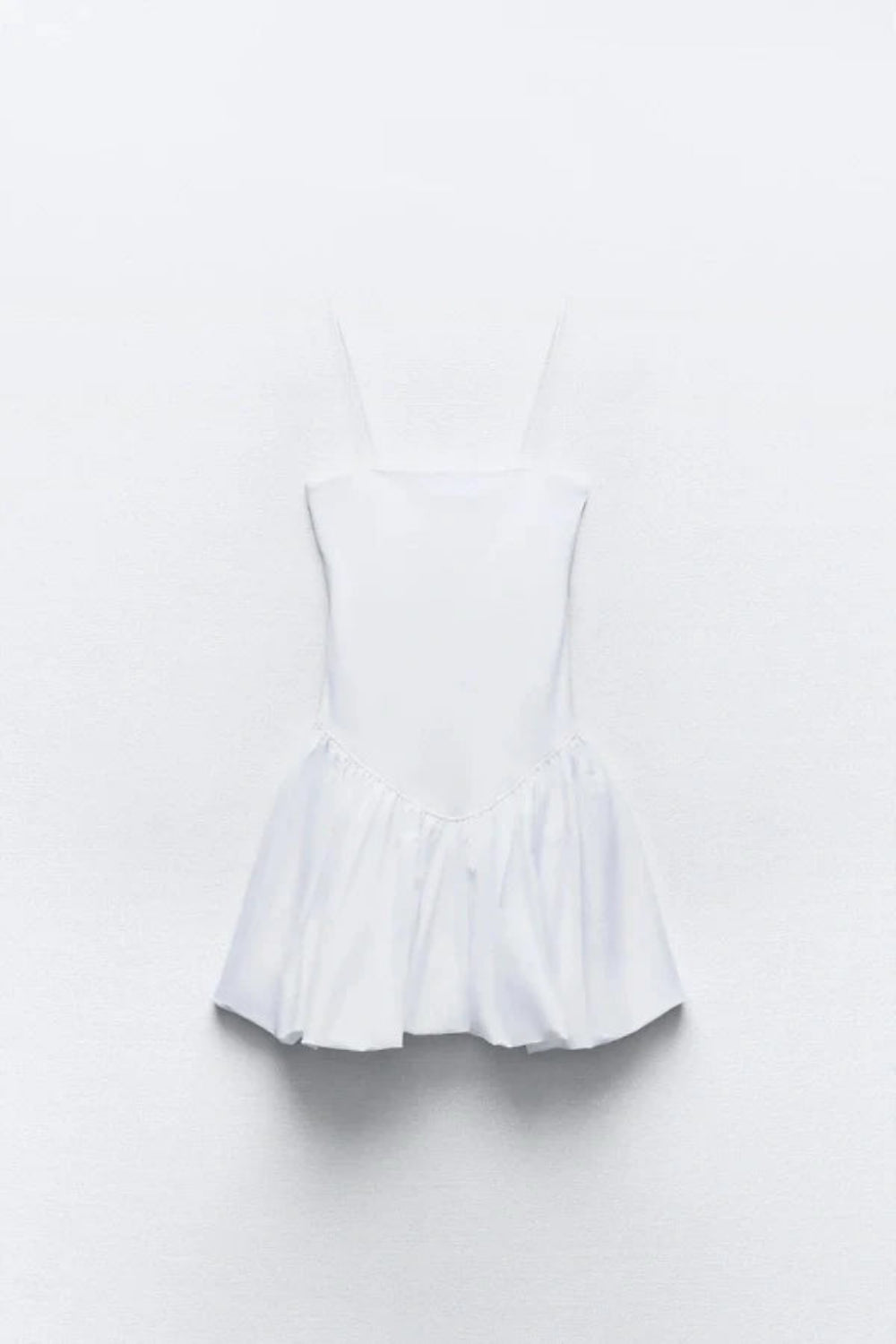 Model wearing the Kouvr white bubble hem mini dress with spaghetti straps