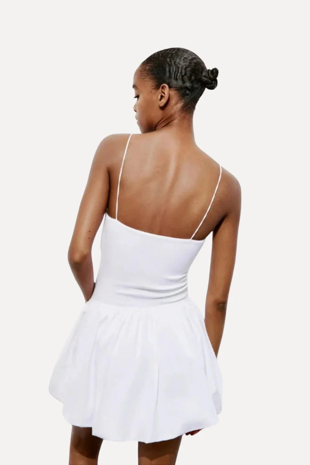 Model wearing the Kouvr white bubble hem mini dress with spaghetti straps