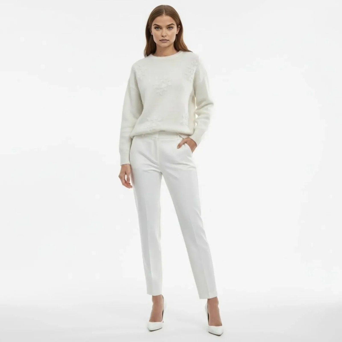 Model wearing the Kouvr white floral appliqué sweater paired with matching white trousers, standing forward.