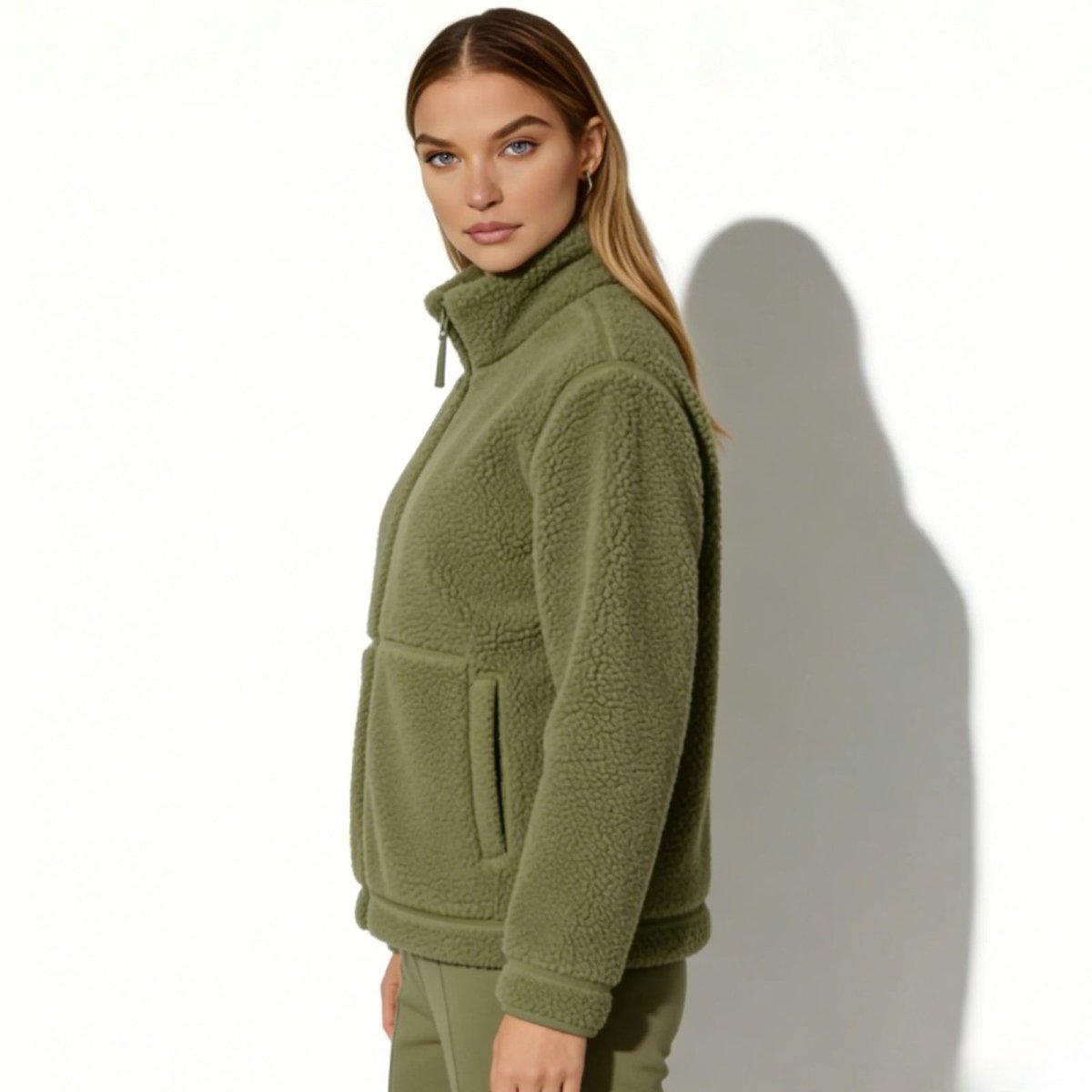 Side profile view of a model in the Kouvr women's army sherpa fleece jacket showing its relaxed fit and stand collar.