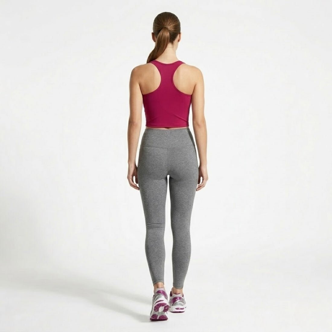Full back view of woman walking away wearing Kouvr berry red racerback crop top and grey performance leggings