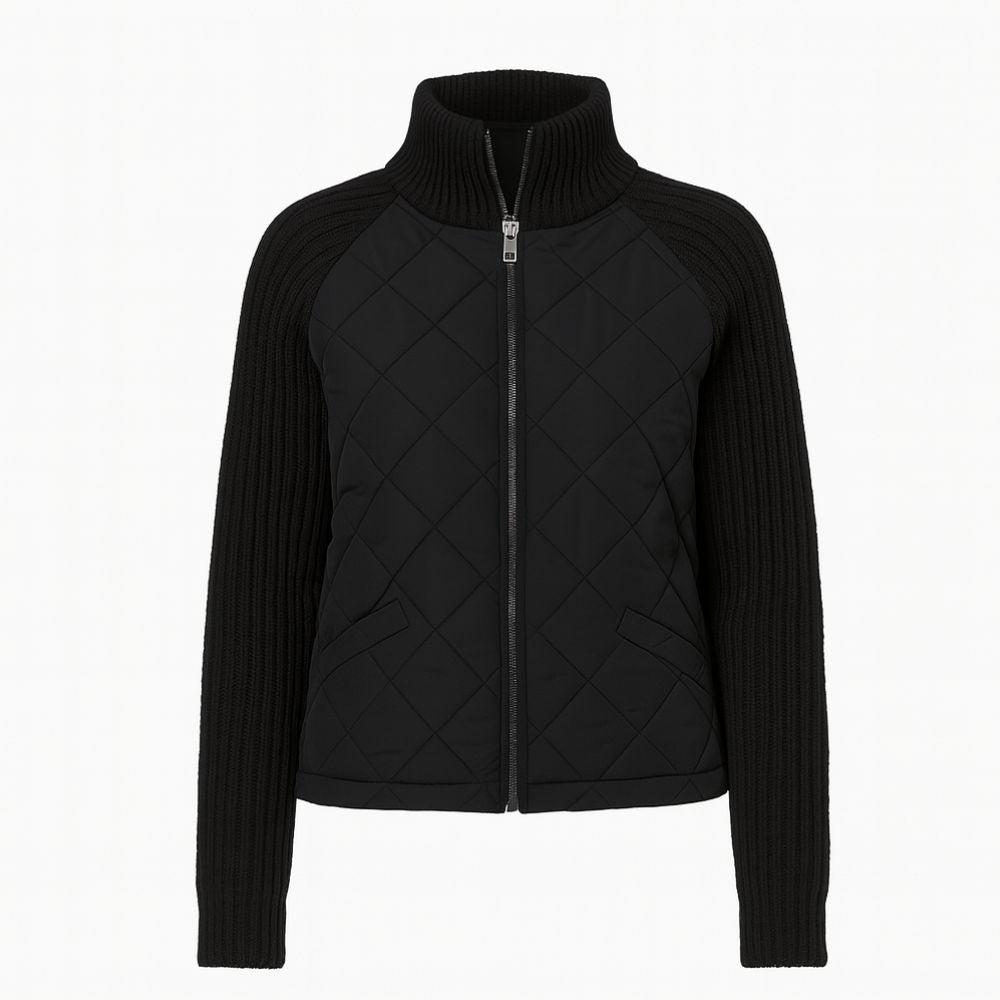 Woman wearing the Kouvr Fashion black quilted jacket with cable knit sleeves and a funnel neck collar, styled for a casual city look