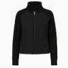 Woman wearing the Kouvr Fashion black quilted jacket with cable knit sleeves and a funnel neck collar, styled for a casual city look