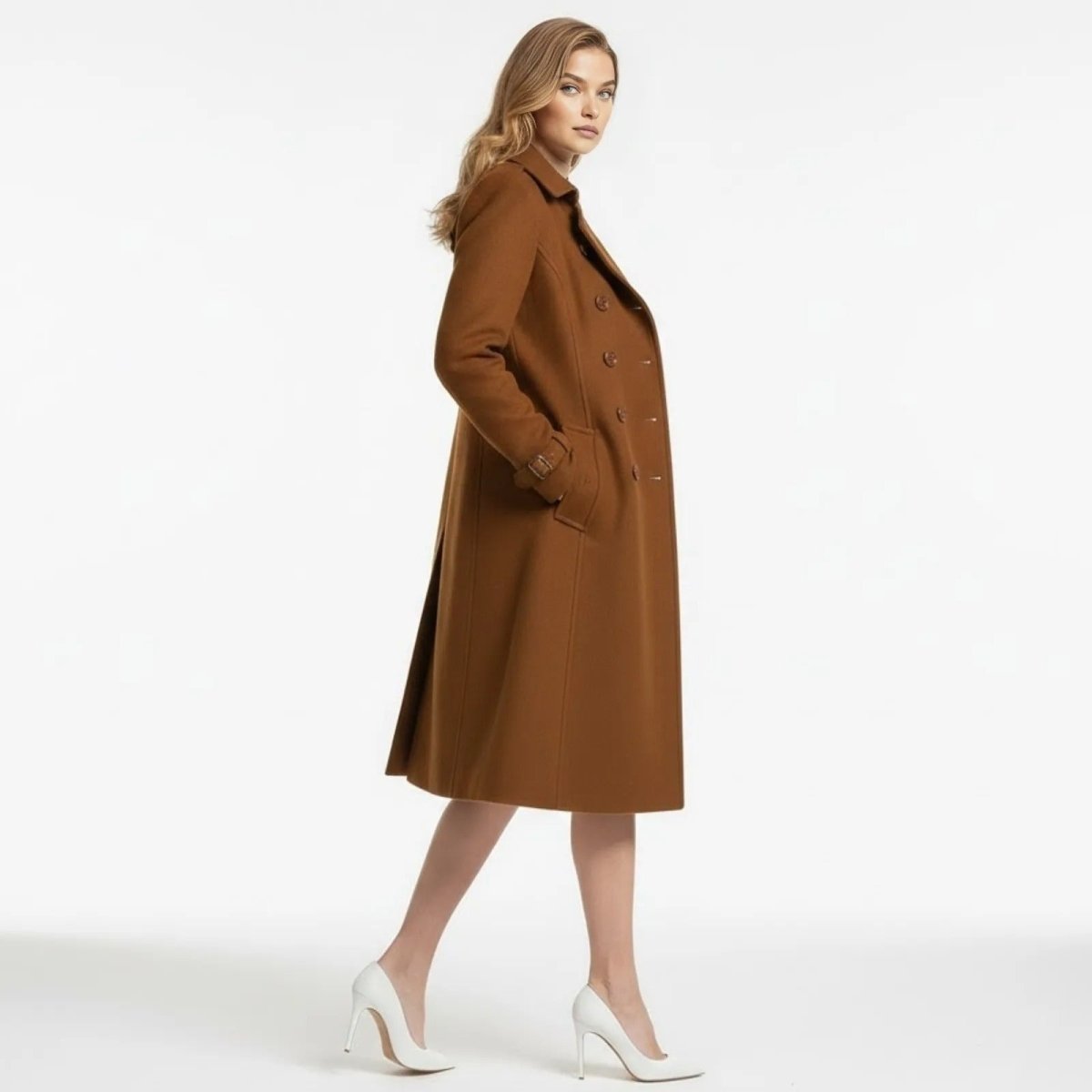 Side profile of a woman walking in a knee-length caramel wool trench coat by Kouvr, highlighting its elegant silhouette and fit.