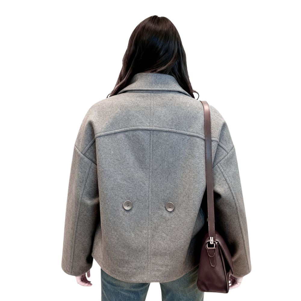 Woman wearing Kouvr's gray wool double-breasted peacoat with a white turtleneck