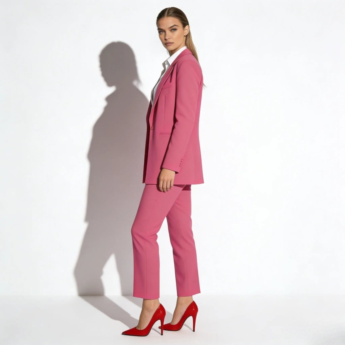 Side profile view of a model in the Kouvr tailored kate pink blazer and matching cropped trousers showing the suit's fit.