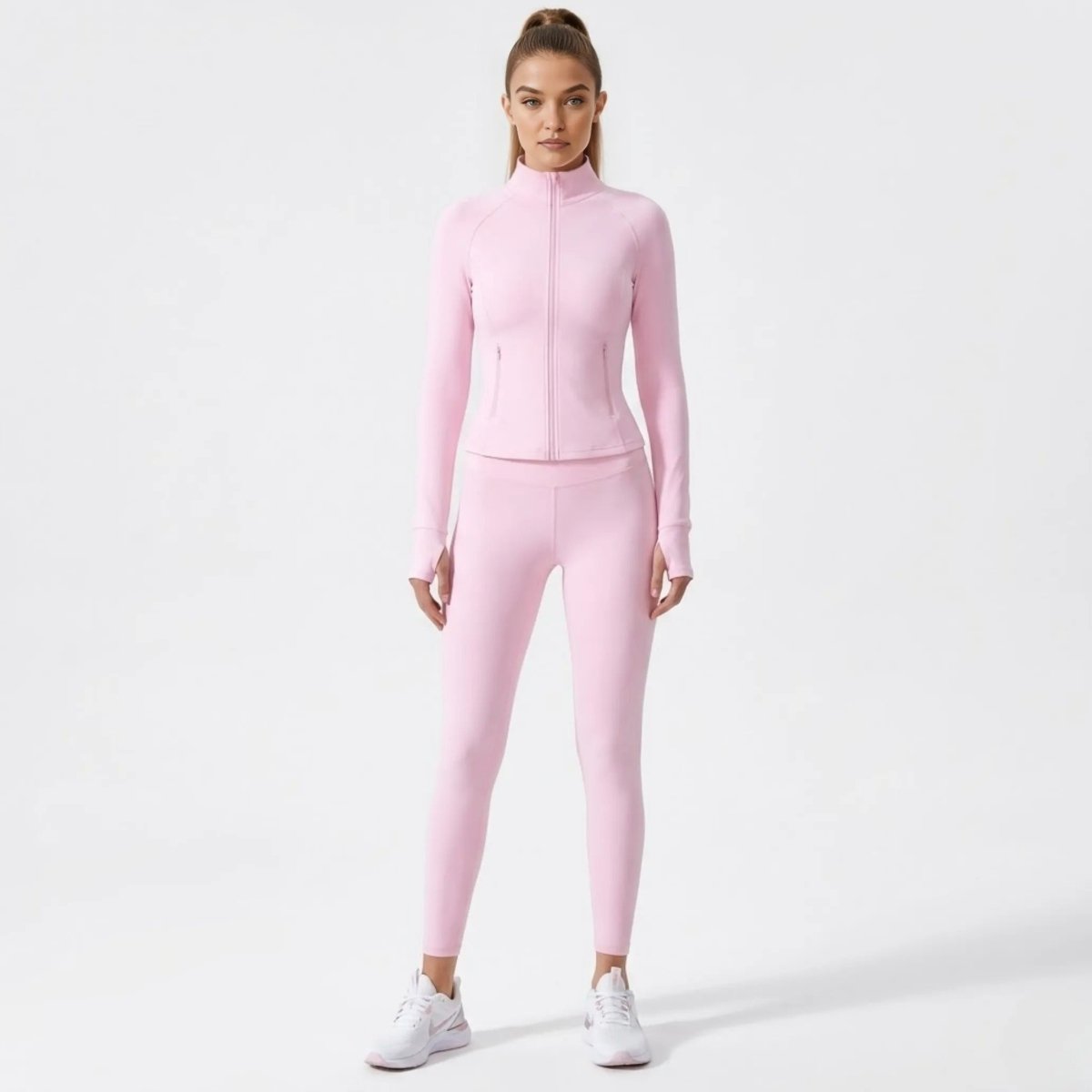 Full body studio shot of female model in matching pink Kouvr activewear set featuring a zip-up jacket and leggings.