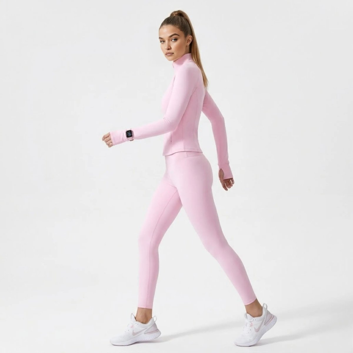 Side profile of woman walking confidently in Kouvr pink workout jacket highlighting functional thumbholes and a sculpted silhouette.