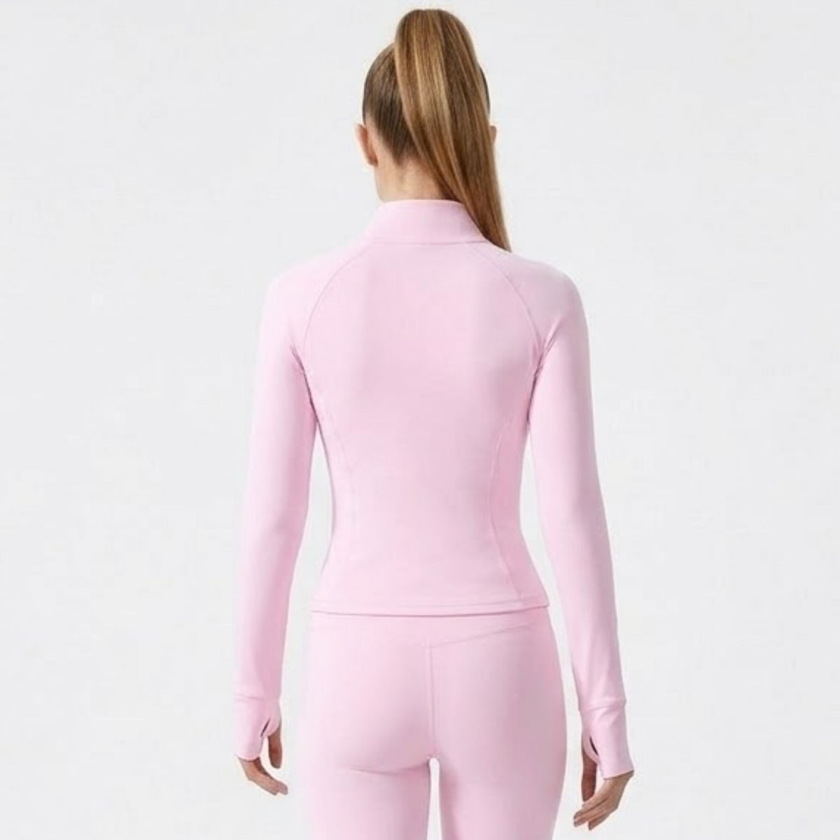 Back view of female model wearing Kouvr pink bodycon athletic track jacket showing tailored contouring seams.