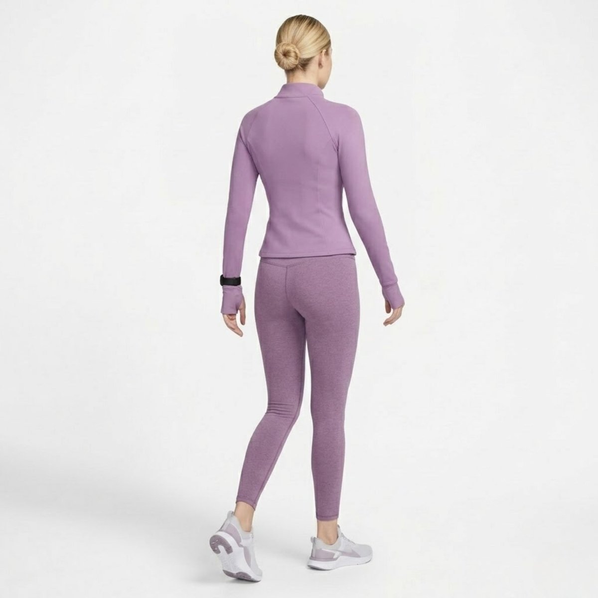Back angled view of woman walking wearing Kouvr purple athletic jacket showing tailored fit