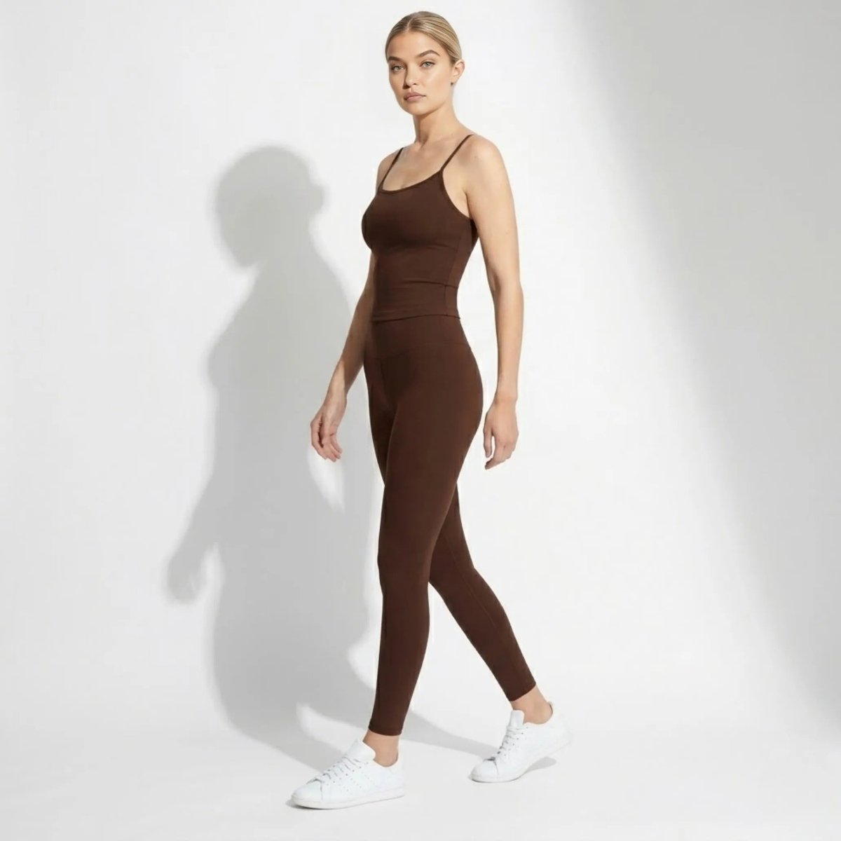 Side profile of model walking wearing Kouvr womens sleeveless lounge top and high waisted bottoms