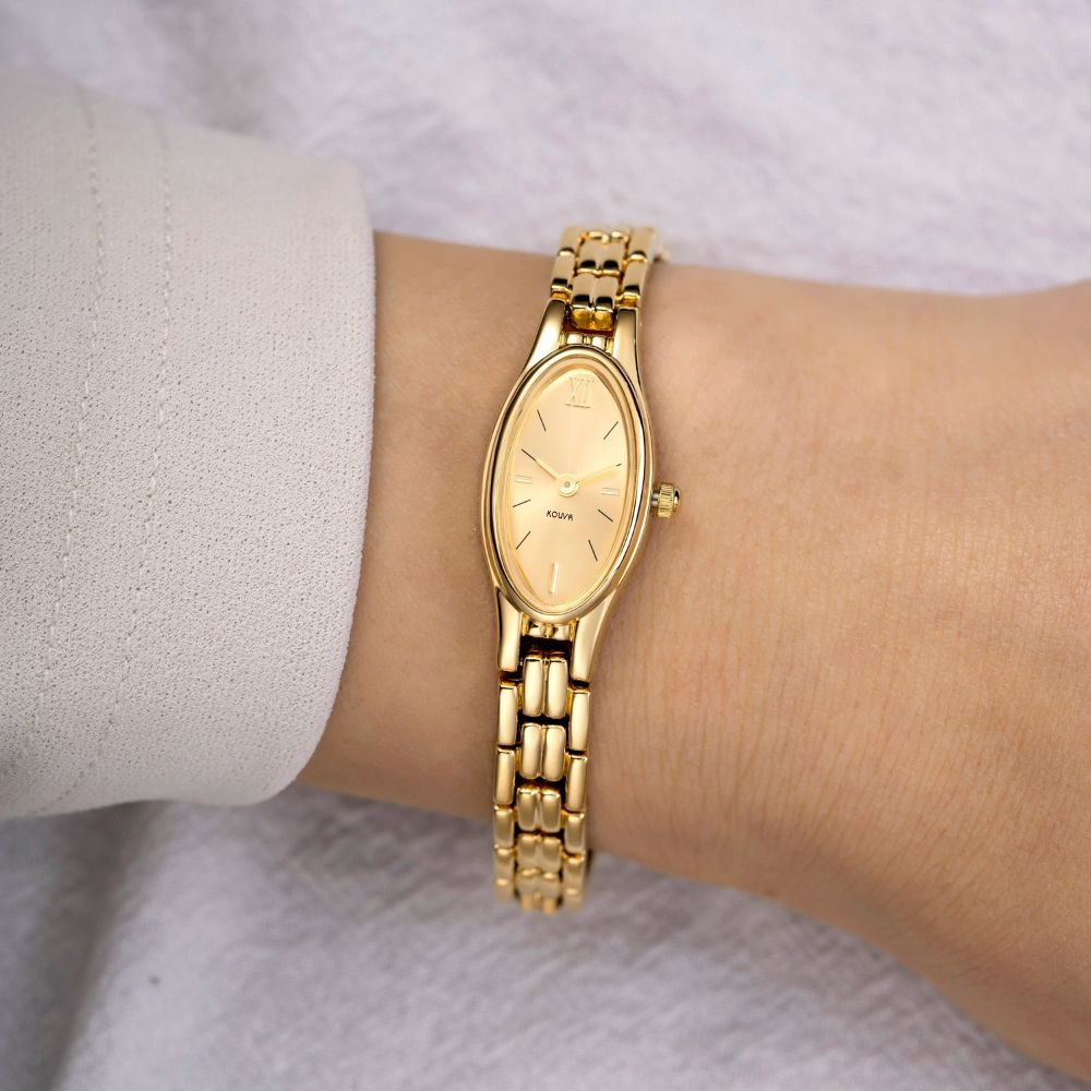 Gold kouvr wristwatch on a person's wrist with a light background